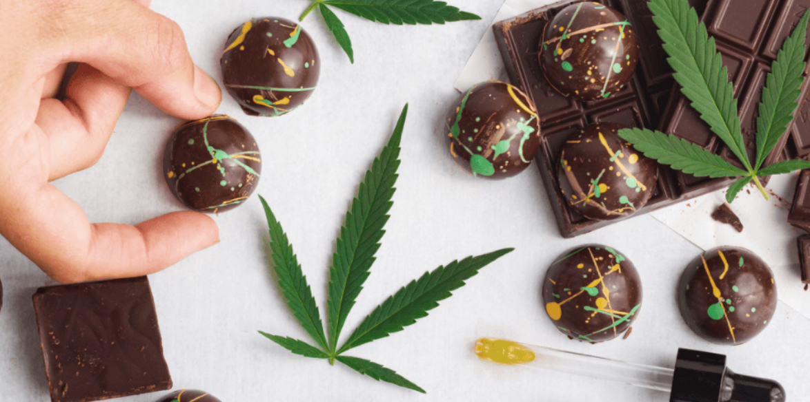 This is a photo of hemp leaves, artisan chocolates that have been painted, and a CBD chocolate bar.